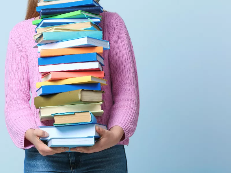 student carrying stack of books